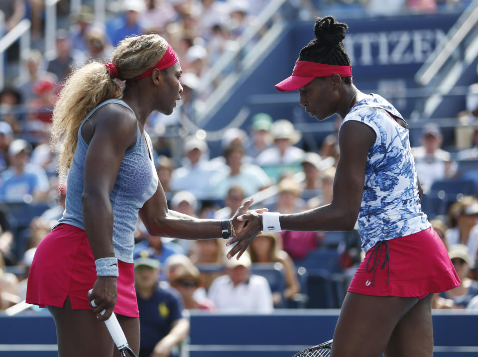 Serena, left, and Venus Williams slap hands between points against Garbine Muguruza and Carla Suarez Navarro, of Spain, during a doubles match at the 2014 U.S. Open tennis tournament, Sunday, Aug. 31, 2014, in New York. (AP Photo/Seth Wenig)