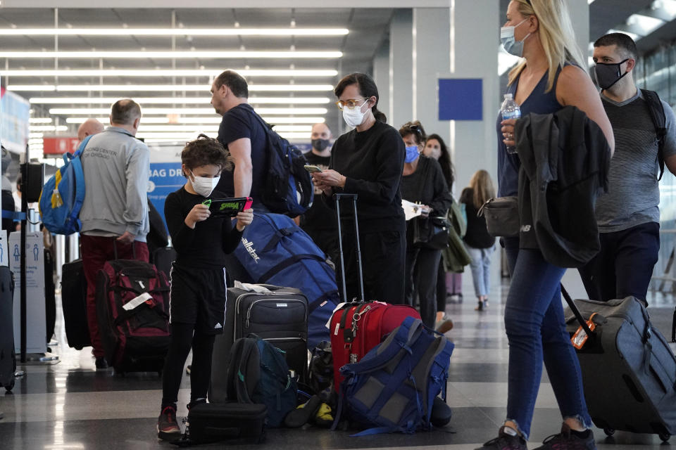 FILE - Travelers are lining up at O'Hare airport in Chicago, Friday, July 2, 2021. The delta and omicron variants of the coronavirus are trying to spoil the holiday spirit, but there are ways to reduce risk while enjoying the festivities. The explosive spread of the omicron variant is causing many to wonder if they should cancel their holiday plans. (AP Photo/Nam Y. Huh, File)