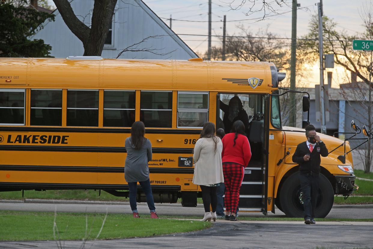 Principal Garry Lawson, right, walks toward Clemens School after getting off a school bus on the first day of his school’s reopening on Wednesday.