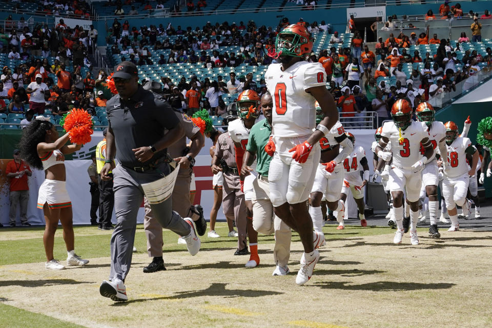 FILE - Florida A&M head coach Willie Simmons, left, runs onto the field before the Orange Blossom Classic NCAA college football game against Jackson State, Sunday, Sept. 4, 2022, in Miami Gardens, Fla. Florida A&M has banned its players from the team's facilities after a rap video featuring some Rattlers was shot in their locker room without proper permission being granted. Coach Willie Simmons told The Associated Press on Saturday, July 22, 2023, the team facility, weight room and access to the stadium field were off limits to all the players until he and the administration could sort out who was involved in the video shoot. (AP Photo/Lynne Sladky, File_