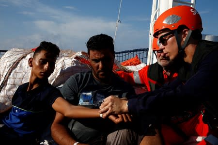 A medic of the German NGO Sea-Eye migrant rescue ship 'Alan Kurdi' fits tags onto migrants claiming to be Tunisians, after they were rescued in the central Mediterranean Sea