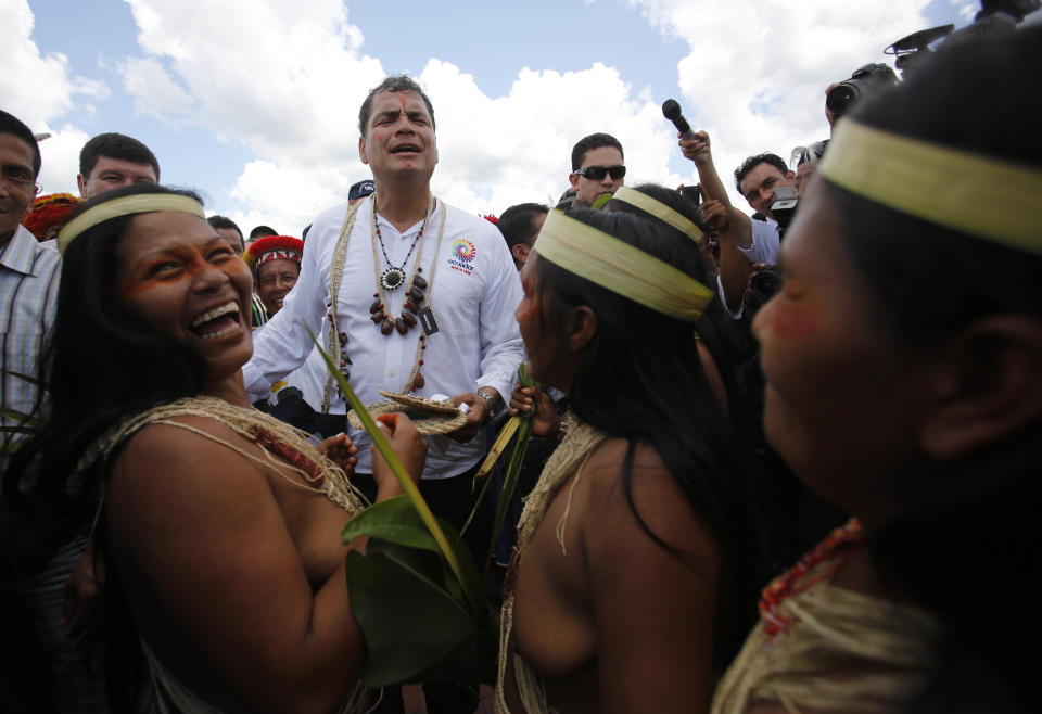 FILE - In this Oct. 1, 2013 file photo, Ecuador's President Rafael Correa is welcomed by Waorani women in the Comunidad del Milenio in the area known as Playas de Cuyabeno in Ecuador's Amazon. Correa inaugurated this village that was built from zero, complete with infrastructure like homes, schools, a library, a clinic and a police force. Correa's critics recognize he has improved Ecuadoreans' self-esteem. All of the candidates competing to succeed him pay some degree of homage to his legacy. (AP Photo/Dolores Ochoa, File)