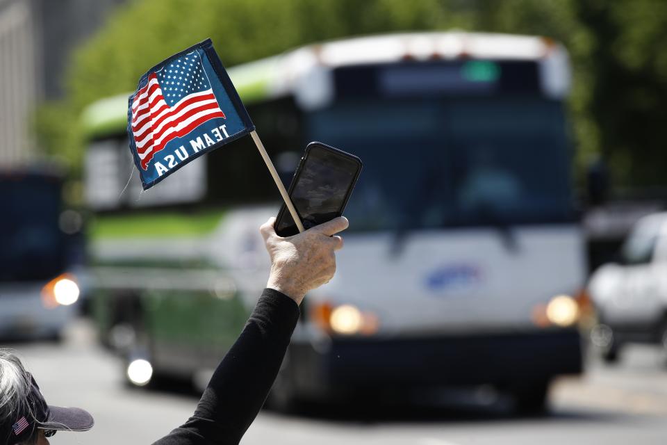 FILE - In this May 13, 2020, file photo, tour guide Barbara Western waves a flag in support of bus and motor coach operators circling National Mall in Washington during a rally to raise awareness of the industry in the wake of the coronavirus outbreak. America's private buses are ground to a halt, and members of the industry say they need federal assistance to help the country get back to work and play. (AP Photo/Patrick Semansky, File)