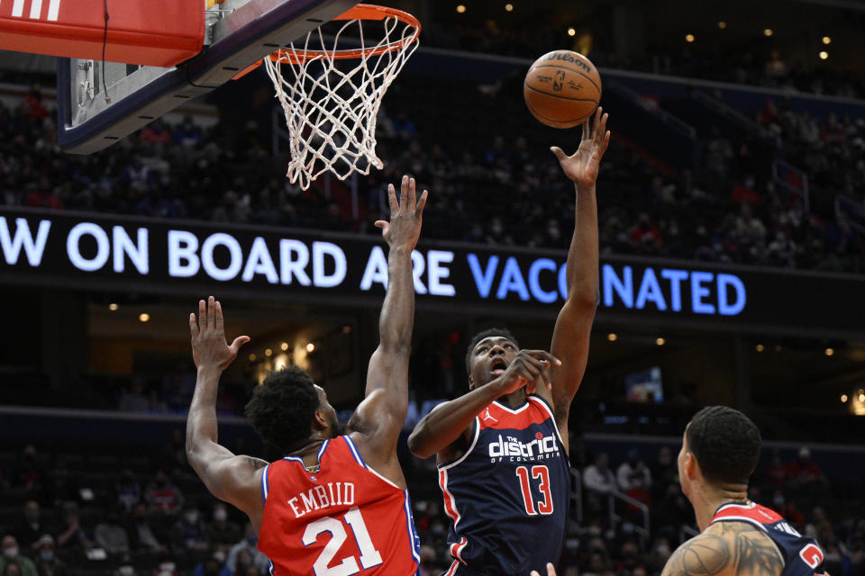 Washington Wizards center Thomas Bryant (13) shoots against Philadelphia 76ers center Joel Embiid (21) during the first half of an NBA basketball game, Monday, Jan. 17, 2022, in Washington. (AP Photo/Nick Wass)