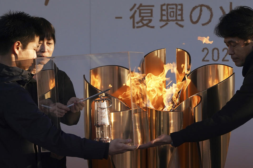 Officials light a lantern from the Olympic Flame at the end of a flame display ceremony in Iwaki, northern Japan, Wednesday, March 25, 2020. IOC President Thomas Bach has agreed "100%" to a proposal of postponing the Tokyo Olympics for about one year until 2021 because of the coronavirus outbreak. (AP Photo/Eugene Hoshiko)