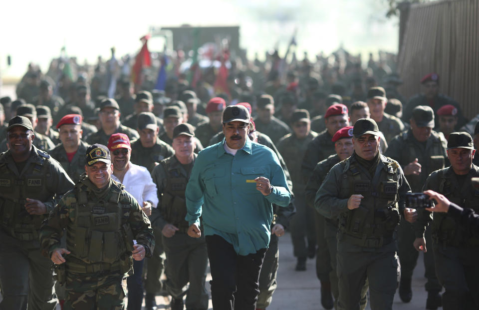 In this photo released to the media by Miraflores presidential palace press office, Venezuelan President Nicolas Maduro, center, jogs alongside his Defense Minister Vladimir Padrino Lopez, right, and soldiers as he visits Ft. Paramacay in Carabobo state, Venezuela, Sunday, Jan. 27, 2019. Opposition lawmaker Juan Guaido has declared himself Venezuela's legitimate leader, as embattled socialist Maduro holds the reins of power. (Marcelo Garcia/Miraflores presidential palace press office via AP)