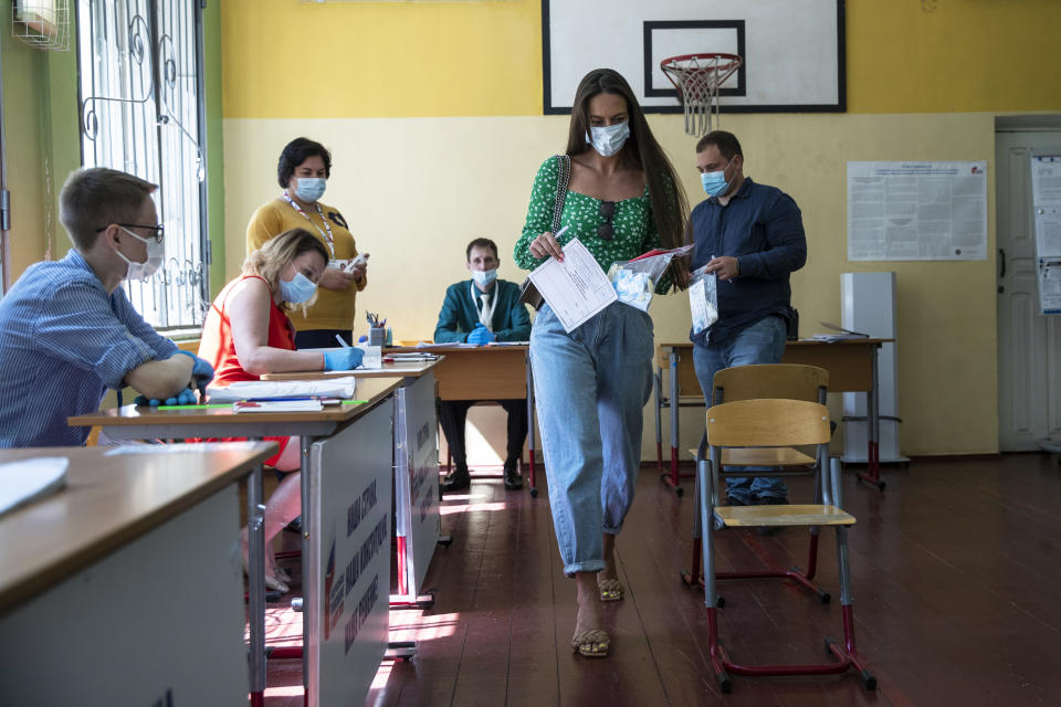 A woman wearing a face mask to protect against coronavirus prepares to cast her ballot at a polling station in Moscow, Russia, Wednesday, July 1, 2020. The vote on the constitutional amendments that would reset the clock on Russian President Vladimir Putin's tenure and enable him to serve two more six-year terms is set to wrap up Wednesday. (AP Photo/Pavel Golovkin)