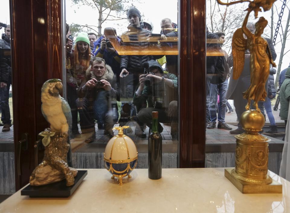 People look through windows of the Mezhyhirya residence of Ukraine's President Yanukovich in the village Novi Petrivtsi