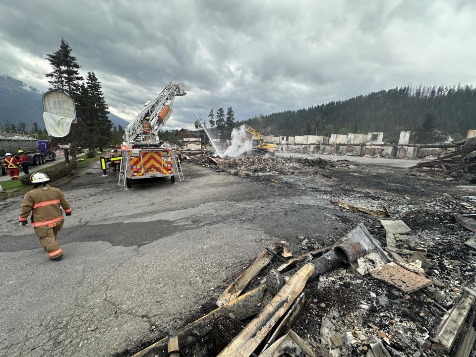 This photo taken on July 26, 2024 shows firefighters working near the remains of a burned building in Jasper, Alberta, Canada, as a wildfire continues to rage. / Credit: TYSON KOSCHIK/POOL/AFP via Getty Images
