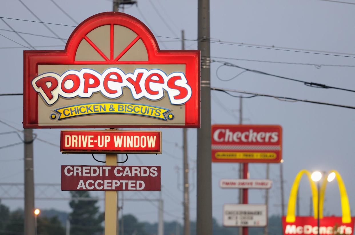 Huntsville, Alabama, USA - August 3, 2011:  Illuminated fast food signs at sunrise.  Popeyes, Checkers, and McDonalds signs on University Drive in Huntsville, Alabama, just west of Jordan Lane.