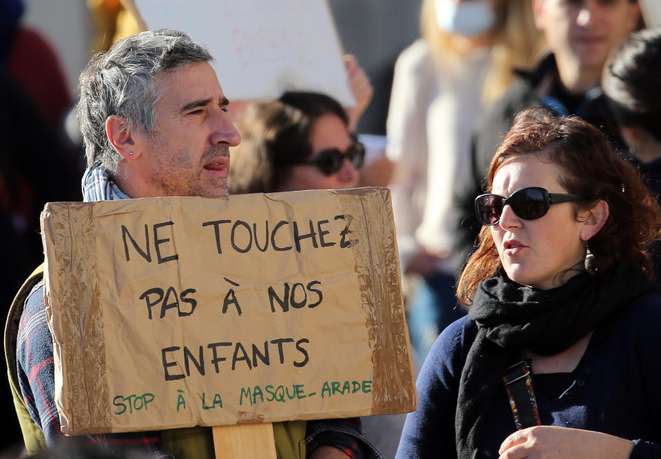 A man holds a placard reads "Don't touch our children" as he demonstrates in Bayonne, southwestern France, against wearing masks at school, Sunday, Nov. 29, 2020. In France, wearing a mask at school is compulsory from 6 years old. (AP Photo/Bob Edme)