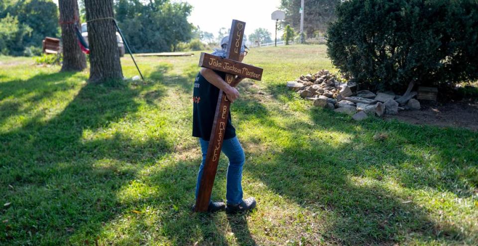 Terri Monteer carries a cross memorializing her son, Jake, to a garden in her yard on Aug. 30 near Bates City. Jake was killed in March when a driver fleeing police struck the motorcycle he was riding.