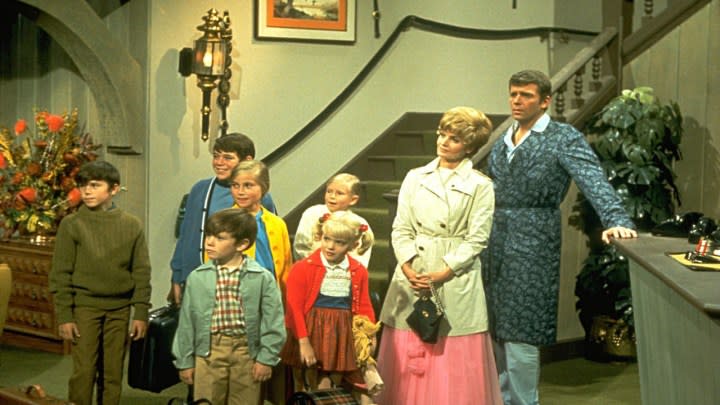 The family on The Brady Bunch standing in the lobby of a hotel.