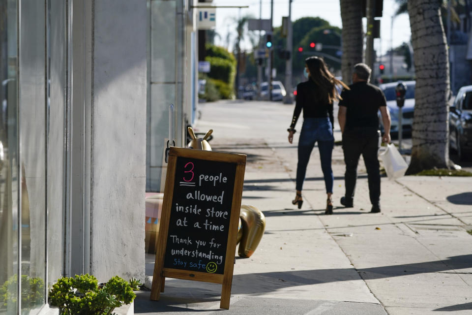 A sign restricting the number of customers stands outside of a shop Wednesday, Nov. 18, 2020, in West Hollywood, Calif. Los Angeles County imposed new restrictions on businesses Tuesday and is readying plans for a mandatory curfew for all but essential workers if coronavirus cases keep spiking. (AP Photo/Ashley Landis)