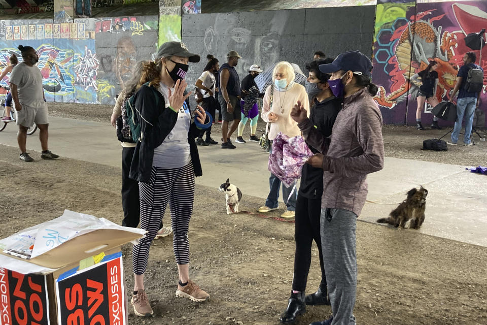 Activist Jan Rivers, left, talks with residents walking along the Atlanta Beltline about progressive movement priorities during an organizing event on April 10, 2021, in Atlanta. Rivers is part of a wide-ranging coalition of progressive organizations trying to pressure Congress on a long list of legislative proposals favored by the left. But the movement faces roadblocks in the evenly divided Senate. (AP Photo/Bill Barrow)