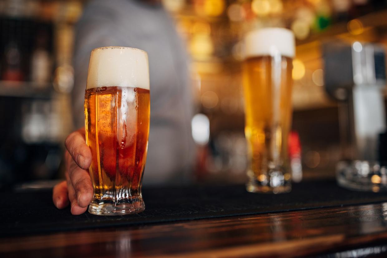 Glass filled with fresh light beer on bar counter.