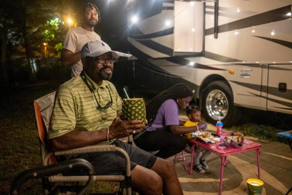 Dr. Stewart Darby, a Columbia, S.C. physician enjoys a pineapple drink while camping with his family on his empty lot in Atlantic Beach and watching the bikers on Friday night.