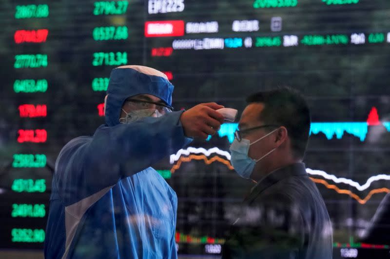 FILE PHOTO: A worker wearing a protective suit takes body temperature measurement of a man inside the Shanghai Stock Exchange building, as the country is hit by a new coronavirus outbreak, at the Pudong financial district in Shanghai