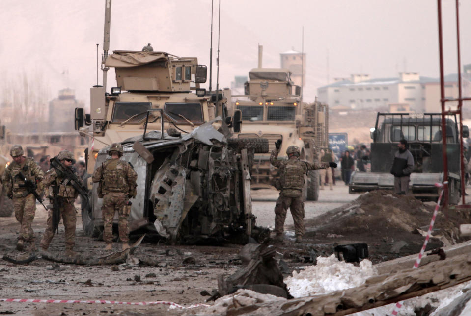 U.S. soldiers search the site where a suicide attacker rammed a car bomb into a NATO convoy killing two foreign civilian contractors, in the Afghan capital Kabul, Afghanistan, Monday, Feb. 10, 2014. The Islamic militant group Hizb-i-Islami claimed responsibility for the attack in eastern Kabul, saying it would drive all foreign forces from Afghanistan. (AP Photo/Rahmat Gul)