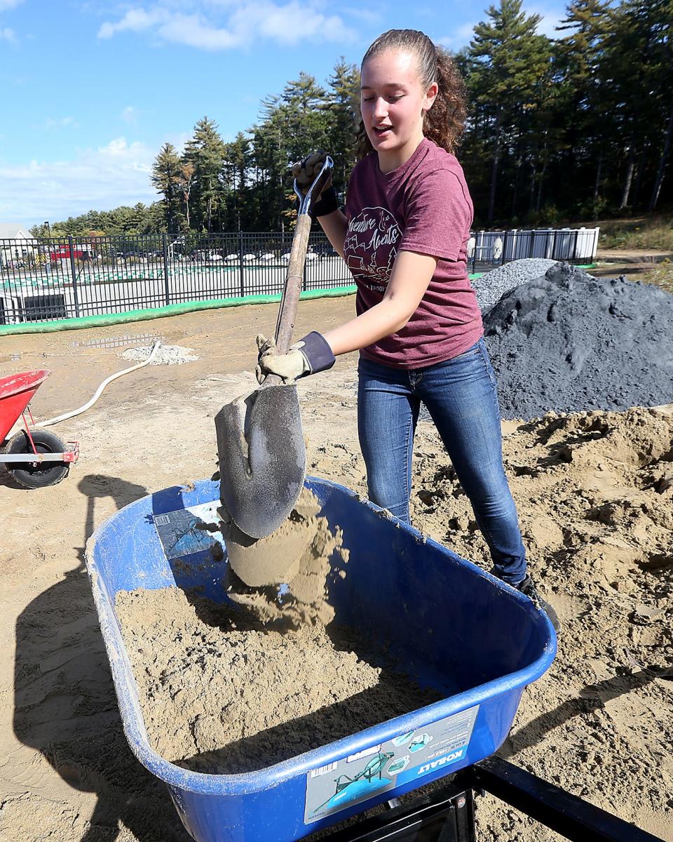 Alyssa Budd, 15, of Troop 424, dumps sand into a wheelbarrow while working on her Eagle Scout project.