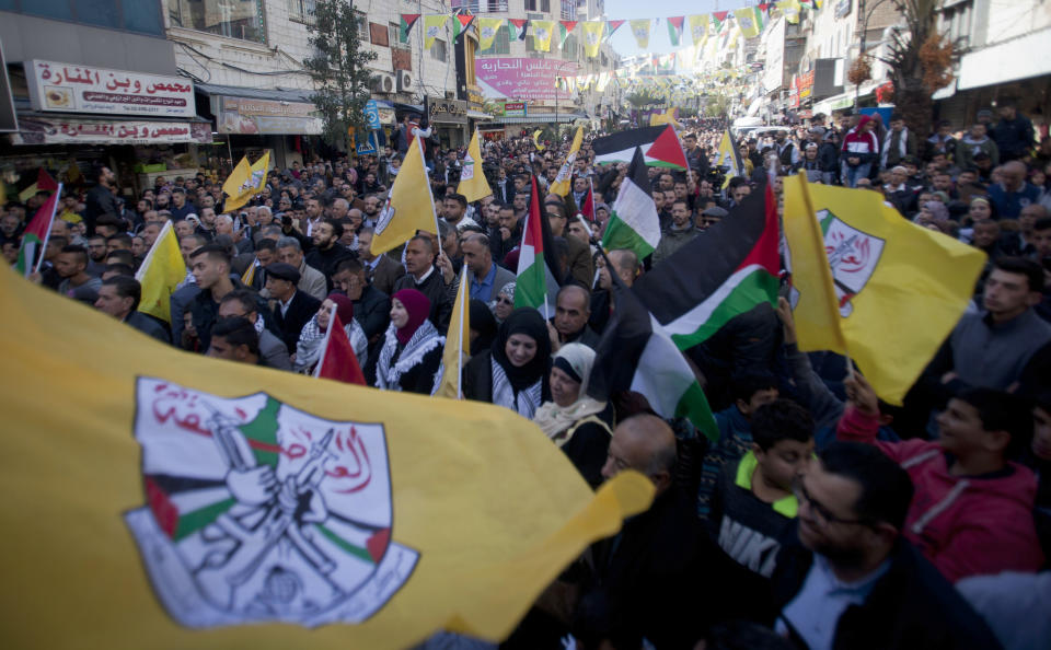 Palestinian wave Fatah and Palestinian flags during a celebration marking the 55th anniversary of the Fatah movement in the West Bank city of Ramallah, Tuesday, Dec. 31, 2019. (AP Photo/Majdi Mohammed)