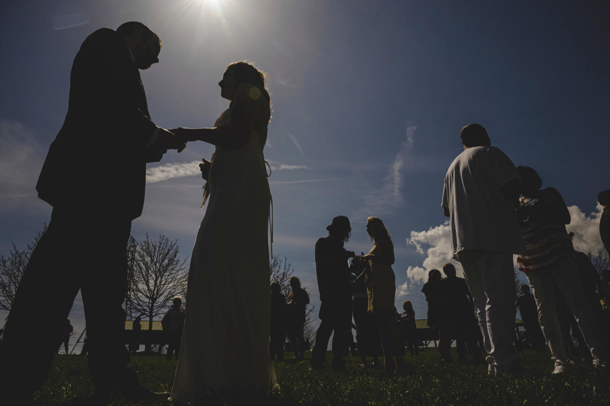 Couples to be wed exchange rings just before totality during a solar eclipse at a mass wedding ceremony at Trenton Community Park, in Trenton, Ohio.