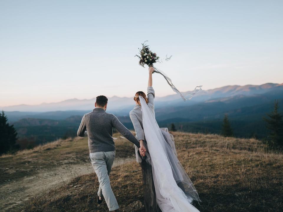 newlywed couple running on a mountainslope