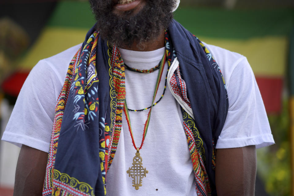 Ras Tashi, a priest, and member of the Ras Freeman Foundation for the Unification of Rastafari, wears his late mother's robes and an Ethiopian Coptic cross around his neck on Sunday, May 14, 2023, in Liberta, Antigua. (AP Photo/Jessie Wardarski)