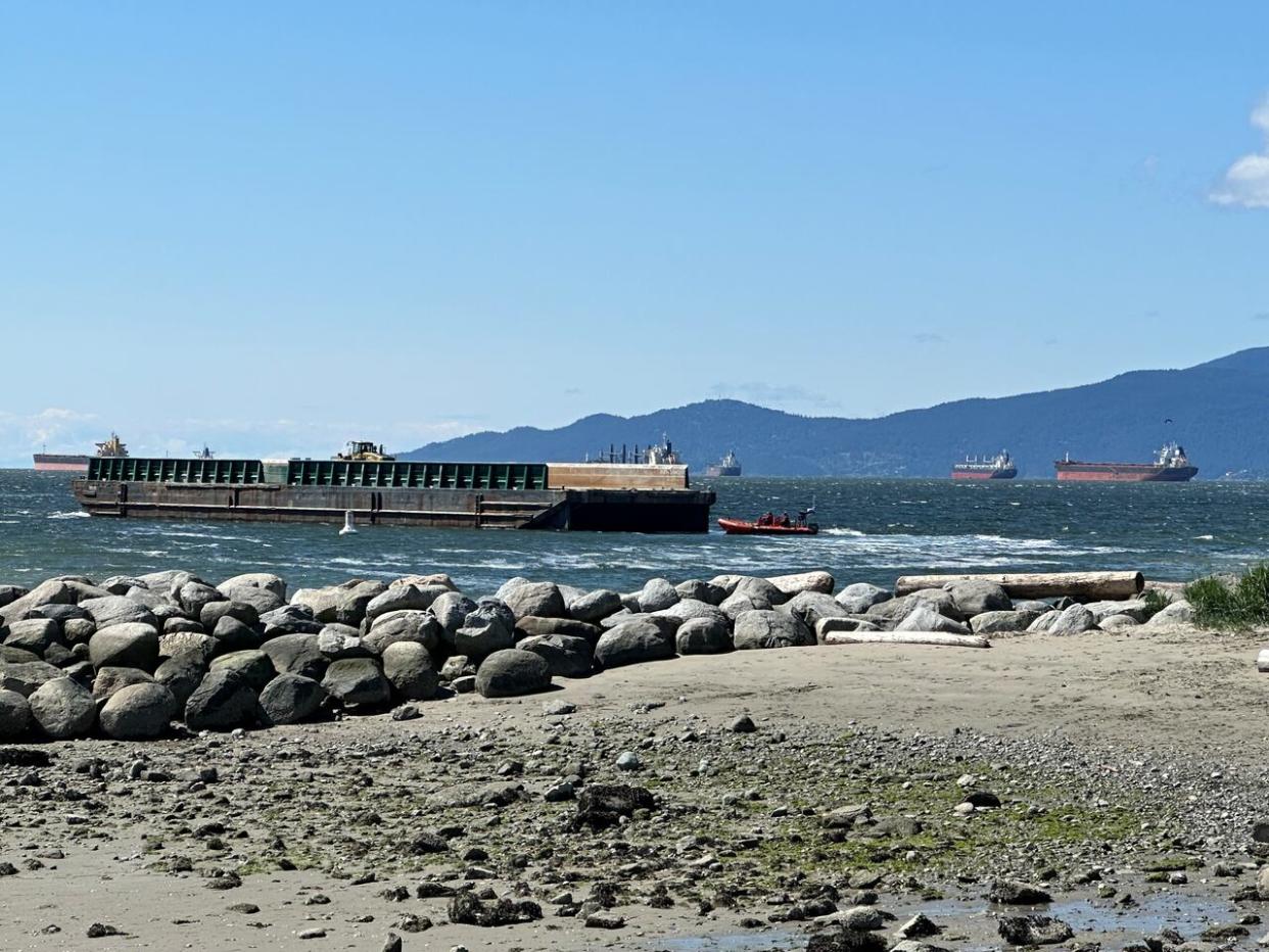 Towing vessels are seen near a barge that seemingly came loose from its moorings near Vancouver's Sunset Beach on Tuesday. (Drew Kerekes/CBC - image credit)