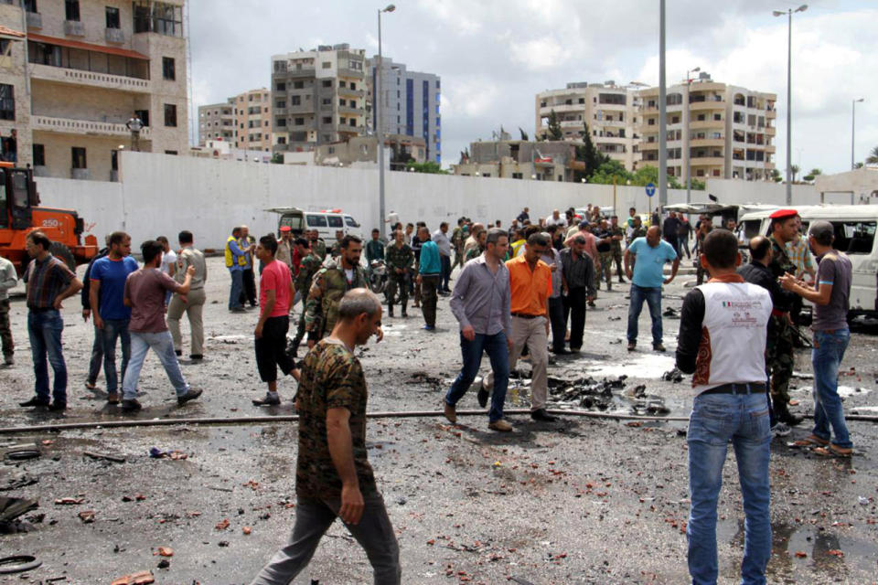 Syrian army soldiers and civilians inspect the damage after explosions hit the Syrian city of Tartus on May 23, 2016. (SANA via Reuters)