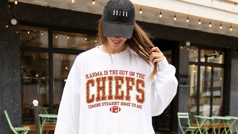 a woman wearing a white sweatshirt that says karma is the guy on the chiefs coming straight home to me in an athletic font