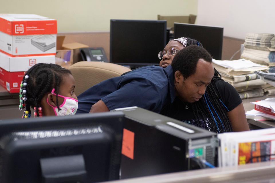 Press operator Brayan Irungu (center) greets his partner and coworker Dwanika Drisdom as he hands off their daughter Tiana, 7, before he starts his shift and Drisdom ends hers at Treasure Coast Newspaper’s production facility Friday, Jan. 14, 2022, in Port St. Lucie.