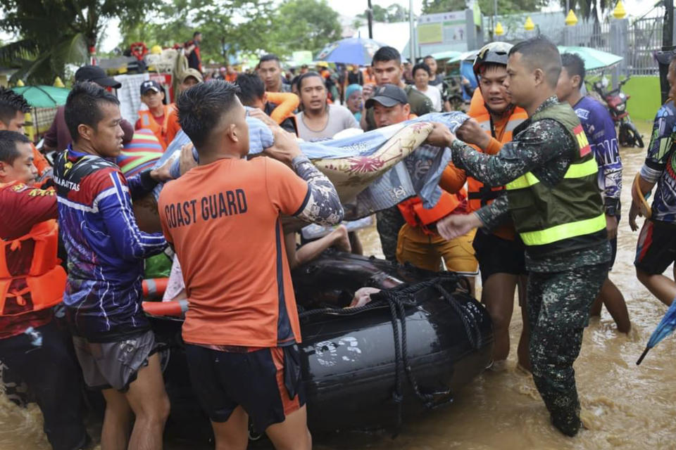 In this photo provided by the Philippine Coast Guard, rescuers carry a resident to safer grounds as floods rose due to Tropical Storm Nalgae at Parang, Maguindanao province, southern Philippines on Friday Oct. 28, 2022. (Philippine Coast Guard via AP)