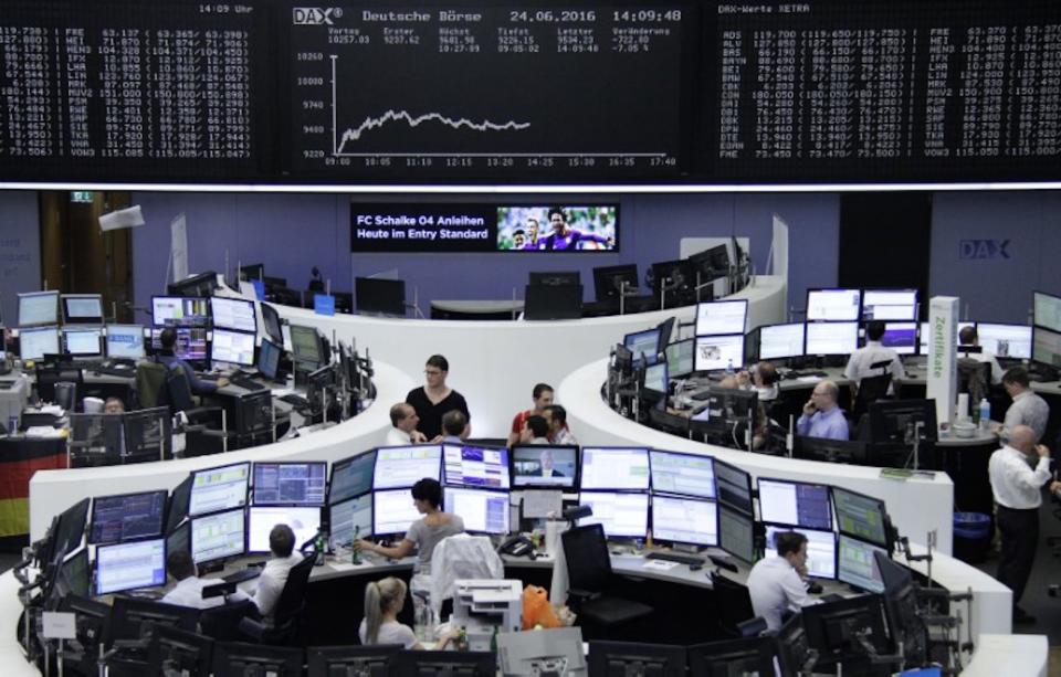Traders work at their desks in front of the German share price index, DAX board, at the stock exchange in Frankfurt, Germany. Photo: Reuters