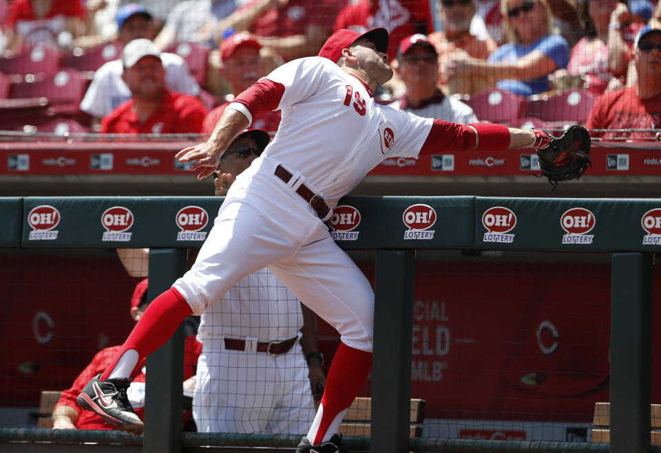 Cincinnati Reds first baseman Joey Votto leans into the dugout to catch a foul ball off the bat of Chicago Cubs' Anthony Rizzo during the first inning of a baseball game, Sunday, Aug. 11, 2019, in Cincinnati. (AP Photo/Gary Landers)