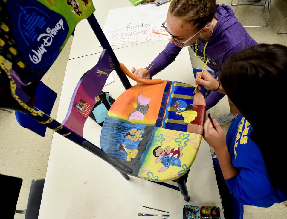 Jefferson High School sophomore Lindsey Gennoe and junior Claire Boggs work on painting different Disney characters on their Disney-themed chair. The chair will be part of this year's Relay of Life Monroe auction.