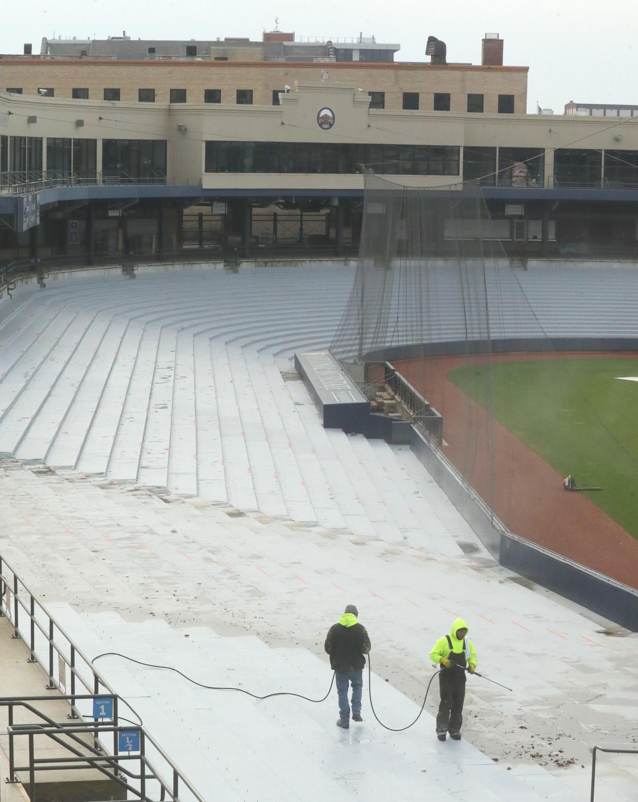Workers power wash the newly sealed seating area on Wednesday in preparation for the installation of new seating at Canal Park in Akron.