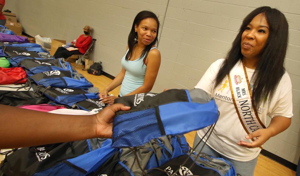 Mia Mintz, left, looks on as Mrs. Black North Carolina Mallory Foxx helps hand out backpacks to students during the Backpack to School Backpack Giveaway event held Saturday, Aug. 12, 2023, at the Erwin Center in Gastonia.