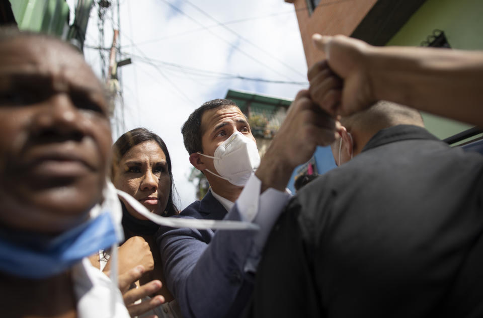 Venezuelan opposition leader Juan Guaidó fist bumps with a resident during a visit to La Lucha neighborhood of Caracas, Venezuela, Thursday, Dec. 10, 2020. Guaidó’s coalition is holding a referendum which culminates on Saturday. It asks Venezuelans at home and abroad to say whether they wish to end President Nicolas Maduro’s rule and hold fresh presidential and legislative elections. (AP Photo/Ariana Cubillos)