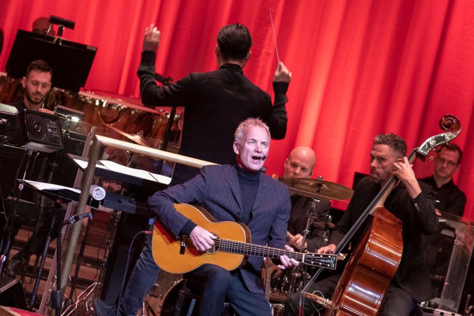 Sting strums a guitar early in his Monday show with the Pittsburgh Symphony Orchestra.
