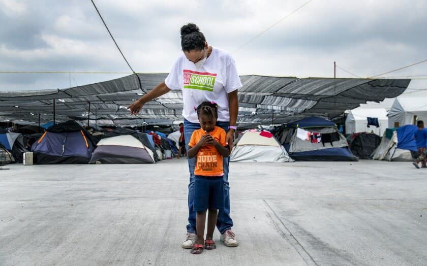 REYNOSA, MEXICO - DECEMBER 6, 2021: A young Haitian migrant leans on Black Mexican-American border activist Felicia Rangel-Samponaro as she walks through Senda De Vida migrant shelter on December 6, 2021 in Reynosa, Mexico. She founded the non-profit Sidewalk School so the children of migrants from Central America and Haiti can learn English and other studies.(Gina Ferazzi / Los Angeles Times)