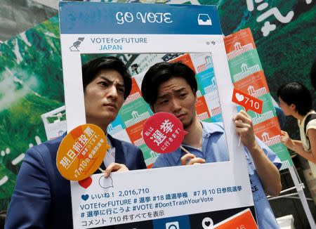 Yohei Saiki (L), 24, head of a conservative non-profit organisation, and Aki Okuda, 24, founding member of the Students Emergency Action for Liberal Democracy (SEALDs), pose with a cardboard Instagram frame calling on youths to vote in the July 10 upper house election, in Shibuya district in Tokyo, Japan June 26, 2016. Picture taken June 26, 2016. REUTERS/Toru Hanai