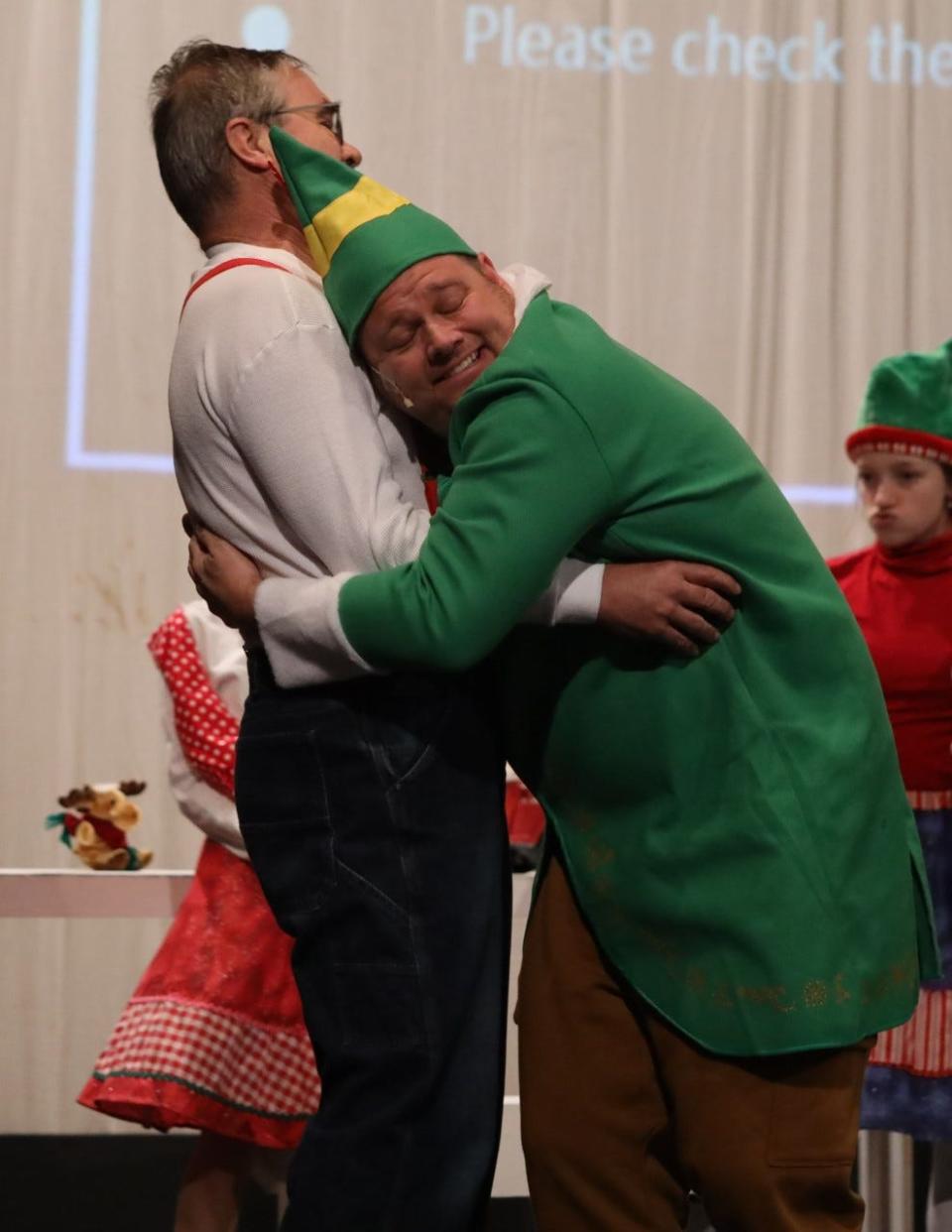 Buddy the Elf, played by Rodgers, hugs Santa Claus played by Hans Kraus.