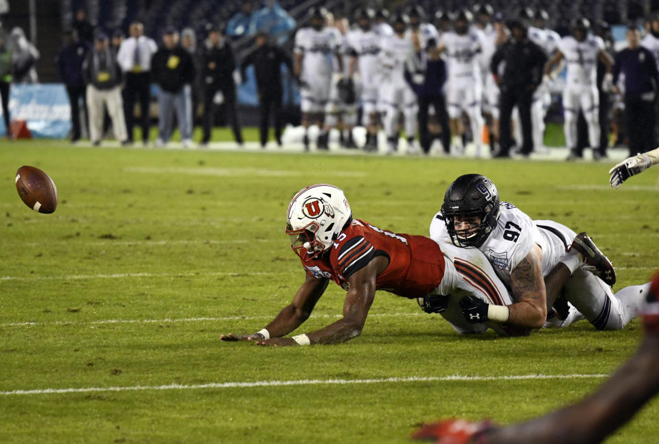 Utah quarterback Jason Shelley (15) fumbles as he is tackled by Northwestern defensive lineman Joe Gaziano (97) as he runs during the second half of the Holiday Bowl NCAA college football game Monday, Dec. 31, 2018, in San Diego. The fumble was picked up by Northwestern and returned for an 86-yard touchdown. (AP Photo/Denis Poroy)