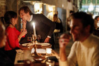 A couple speak as they enjoy a drink and candle lit dinner at Brasserie Surrealiste in Brussels, Wednesday, Sept. 28, 2022. A group of restaurant owners in Brussels has imagined how a future without gas and electricity would look like for gourmets. Dinner guests, served at the Brasserie Surrealiste and cooked by Racines restaurant employees, were the first to experience it: No ovens, no stoves, no hot plates, no coffee machines and no light bulbs. (AP Photo/Olivier Matthys)