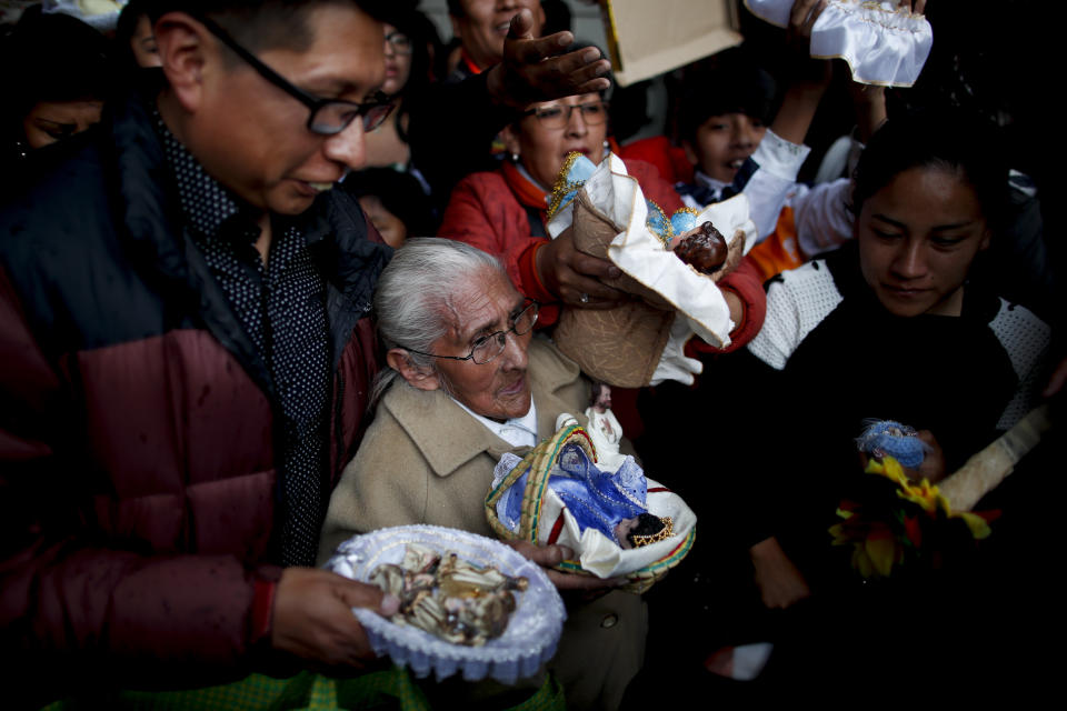 Varias personas hacen cola para que un sacerdote bendiga sus muñecos de Jesús a la salida de la Misa de Reyes en la Iglesia de San Francisco de La Paz el 6 de enero del 2020. Afuera de la iglesia, guías espirituales indígenas realizaban otras ceremonias tradicionales de la cultura andina. (AP Photo/Natacha Pisarenko)