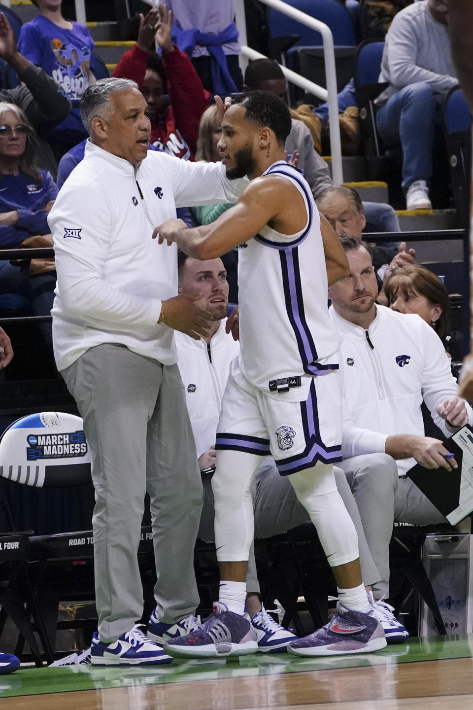 Kansas State assistant coach Kevin Sutton talks with guard Markquis Nowell (1) near the bench during the team's first-round college basketball game against Montana State in the men's NCAA Tournament on Friday, March 17, 2023, in Greensboro, N.C. The days of head coaches leaning primarily on their three assistants and maybe a director of basketball operations in running a top-tier program are gone. Sutton joined Kansas State’s staff as “director of strategies” with duties such as formulating game plans, scouting and film review. (AP Photo/John Bazemore)