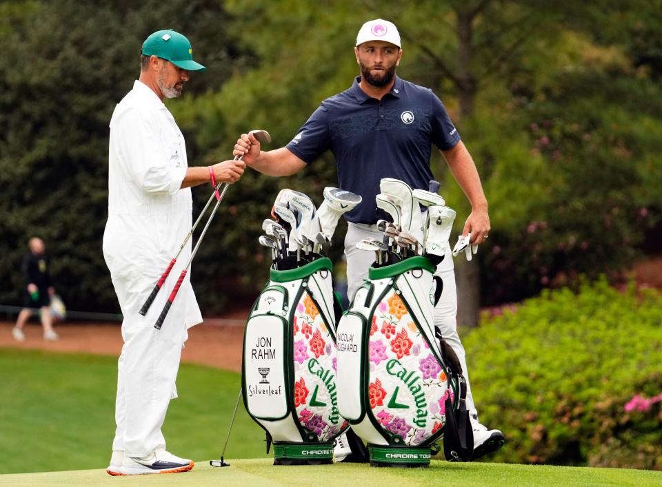 Jon Rahm exchanges clubs with caddie Adam Hayes during Tuesday's practice round at Augusta National, ahead of his hosting of the Champions Dinner on Tuesday night.