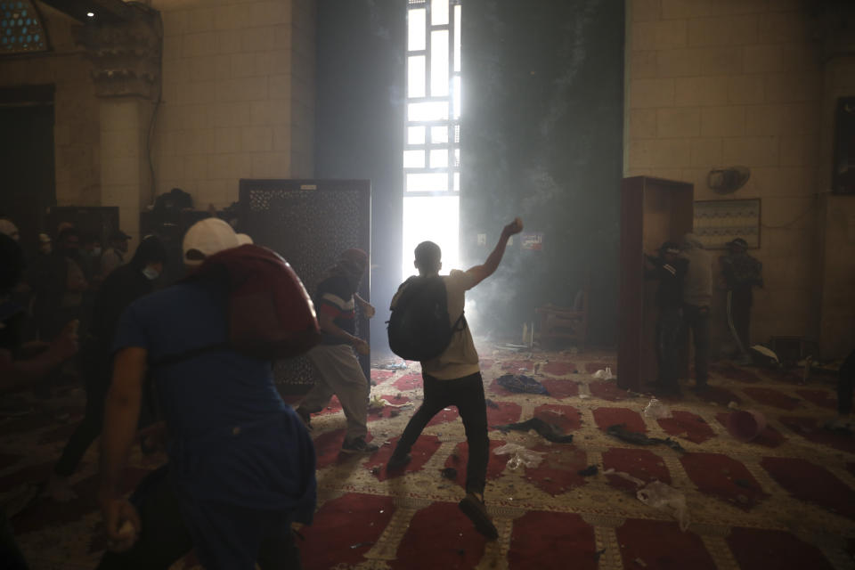 Palestinians inside the Al-Aqsa mosque clash with Israeli security forces at the Al Aqsa Mosque compound in Jerusalem's Old City Monday, May 10, 2021. Israeli police clashed with Palestinian protesters at a flashpoint Jerusalem holy site on Monday, the latest in a series of confrontations that is pushing the contested city to the brink of eruption. Palestinian medics said at least 180 Palestinians were hurt in the violence at the Al-Aqsa Mosque compound, including 80 who were hospitalized. (AP Photo/Mahmoud Illean)