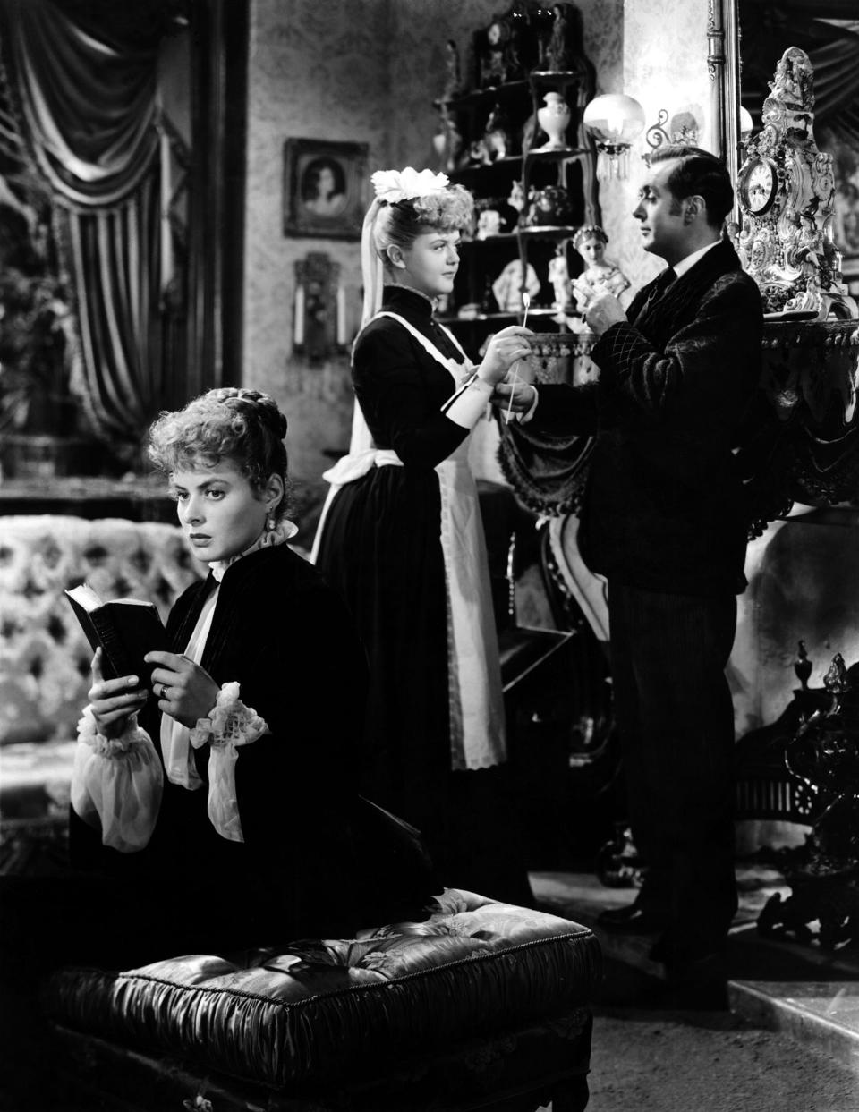 Ingrid Bergman holding a book and Angela Lansbury behind her as a maid